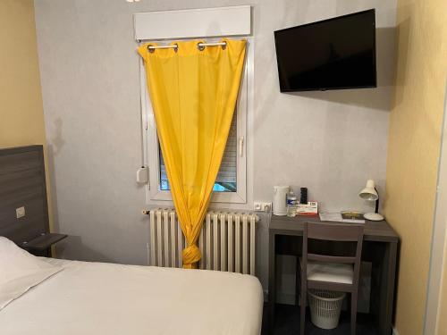 - une chambre avec un lit et un bureau avec un rideau jaune dans l'établissement Logis Hotels - Le Saint Clément - Hotel Restaurant, à Saint-Médard-de-Guizières