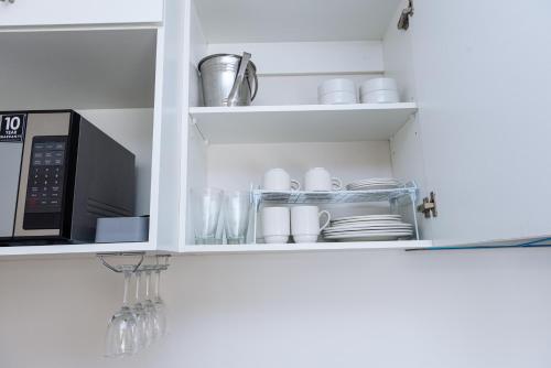 a kitchen cupboard with dishes and a microwave at Glorystar The Millennial Umhlanga in Durban