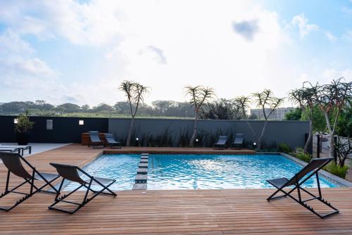 a swimming pool with chairs on a wooden deck at Glorystar The Millennial Umhlanga in Durban