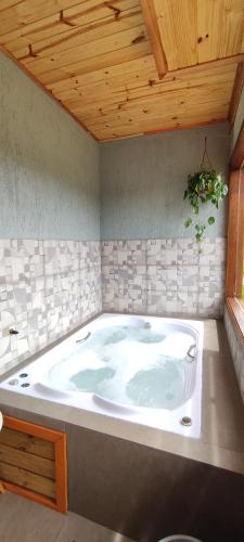 a large bath tub in a room with a wooden ceiling at Cabana Santa Cruz in São Francisco de Paula