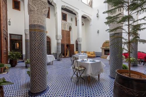a room with tables and chairs in a building at Palais Nazha Fes - Luxury Lodging in Fès