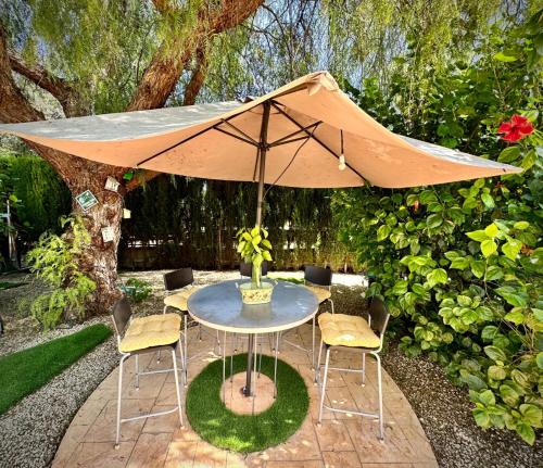 a table and chairs with an umbrella in a garden at Villa MS in Alicante