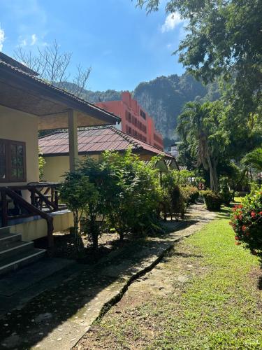 a building with trees and a mountain in the background at Adam Bungalows in Ao Nang Beach
