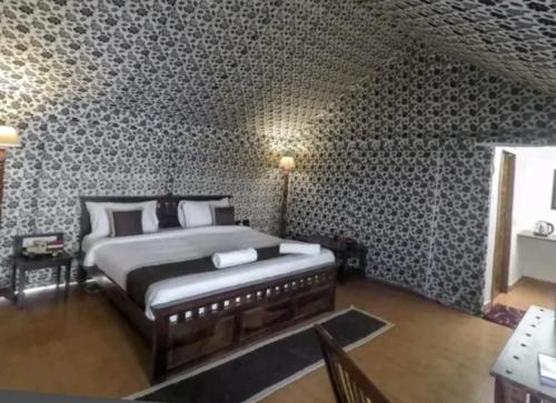 a bedroom with a bed in a room with wallpaper at desert Safari Jaisalmer in Sām