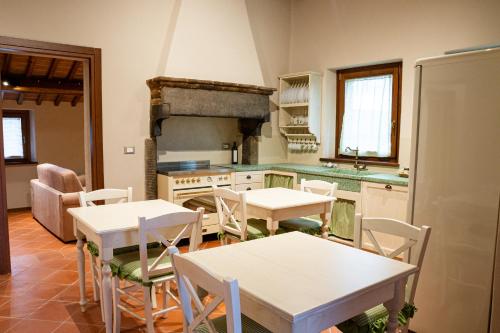 y cocina con mesas y sillas blancas y fogones. en B&B Casa del Pietro, en Pieve San Giovanni