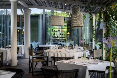 una sala da pranzo con tavoli e sedie bianchi di Villa Regina - MarePineta Resort a Milano Marittima