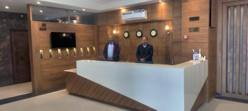 Due uomini in piedi davanti a un bancone in una hall di The City Life Hotel a Zirakpur