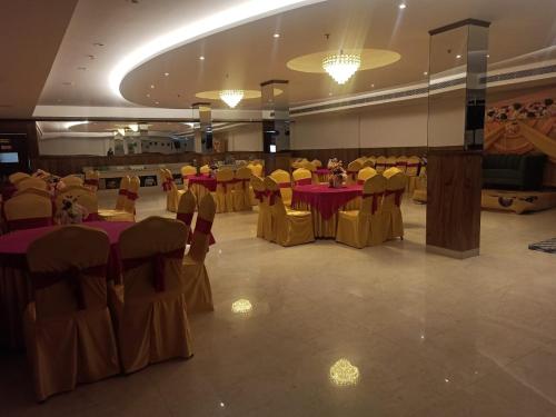 un salón de banquetes con mesas rojas y sillas amarillas en The City Life Hotel, en Zirakpur
