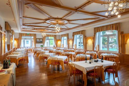 una sala da pranzo con tavoli e sedie bianchi di Hotel Vioz a Peio Fonti