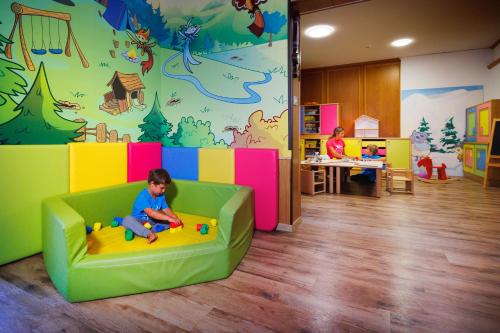 a child sitting on a couch in a play room at Hotel Vioz in Peio Fonti