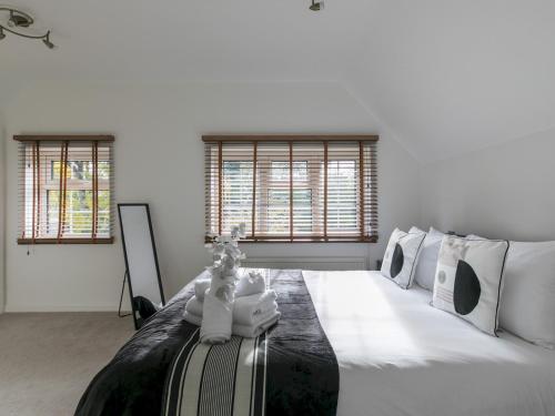 a white bedroom with a large bed with white pillows at Pass the Keys Spacious Home in Picturesque Village of Wraysbury in Wraysbury