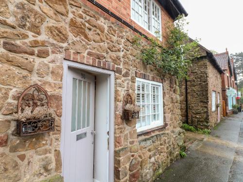 a stone house with a white door and a street at 36 Main Street in Derby