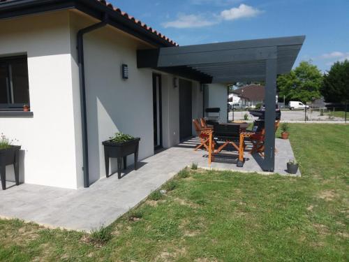 eine Terrasse mit einer schwarzen Pergola sowie einem Tisch und Stühlen in der Unterkunft Le gite de la battere in Saubusse