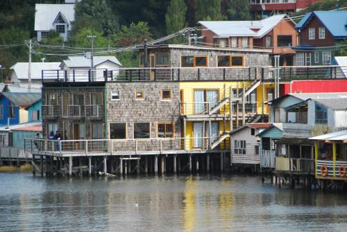 a group of houses on a dock next to the water at Palafito 1326 Hotel Boutique Chiloé in Castro