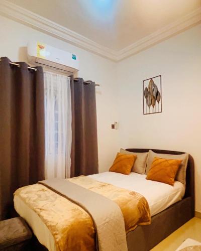 ein Schlafzimmer mit einem Bett mit braunen Vorhängen in der Unterkunft Taari's Place in Accra