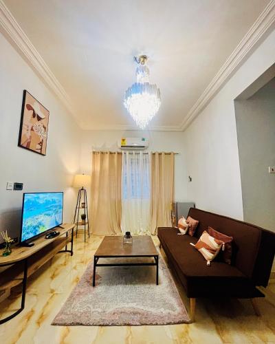 ein Wohnzimmer mit einem Sofa und einem TV in der Unterkunft Taari's Place in Accra