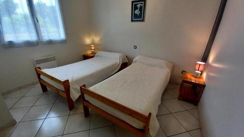 dwa łóżka w pokoju z dwoma lampami na stołach w obiekcie Le gite gravieres w mieście Buglose