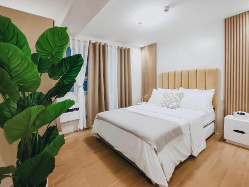 um quarto com uma cama branca e uma planta em The Constant Cove – 3BR Condo Near Airport, Samal Island & Malls em Davao