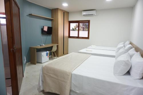 um quarto com uma cama com almofadas brancas e uma janela em Pousada Brisas da Natureza em Satuba