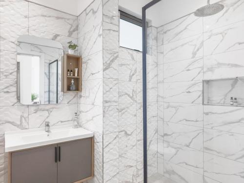 biała łazienka z umywalką i prysznicem w obiekcie Résidence Coastal View - Privilege Appartement in the heart of Grand-Baie w mieście Grand Baie
