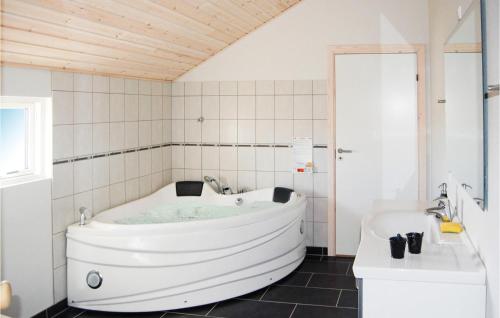 a white tub in a white tiled bathroom at Beautiful Home In Rdby With 4 Bedrooms, Sauna And Wifi in Kramnitse