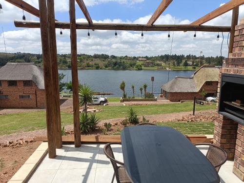 a table and chairs on a patio with a view of a lake at Sedgefield Lodge in Witbank