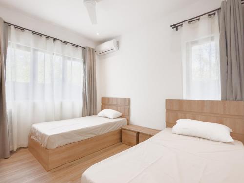 a bedroom with two beds and a window at Résidence Coastal View - Privilege Appartement in the heart of Grand-Baie in Grand Baie