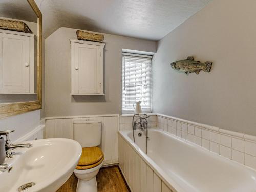 a bathroom with a tub and a toilet and a sink at Orions Cottage in Chilham