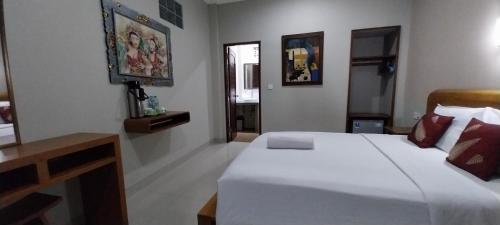 a bedroom with a large white bed and a desk at Umayuri Inn in Ubud