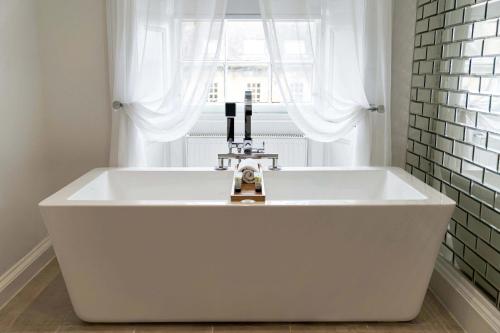 a white bath tub in a bathroom with a window at Hanover 71 Suites in Edinburgh