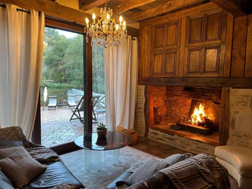 a living room with a fireplace and a chandelier at Moulin de Cambelong- Emilie & Thomas in Conques-en-Rouergue