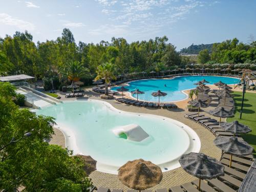 an overhead view of a large swimming pool with umbrellas at 4 Mori Family Village - Villaggio per Famiglie in Muravera