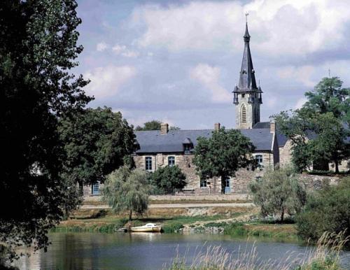 una iglesia con campanario y un río con un edificio en randonnées à Sert, en La Chapelle-de-Brain