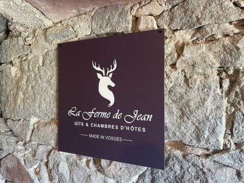 a sign on a stone wall with a sign for a restaurant at La Ferme de Jean entre lacs et montagnes in Saulxures-sur-Moselotte