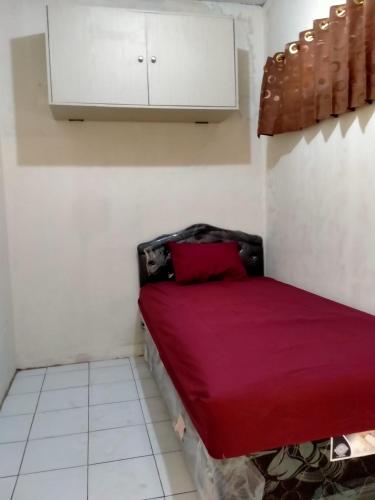 um pequeno quarto com uma cama vermelha e um armário em GH SIRNAMISKIN em Bandung