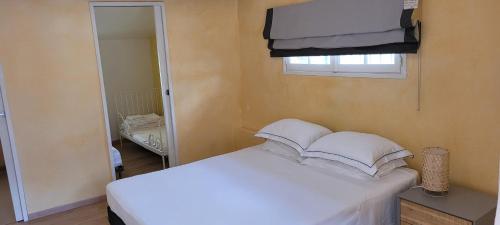 een slaapkamer met een bed met witte lakens en een spiegel bij Catalan Cottage terrace and secure garage in Rigarda
