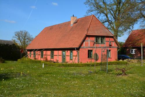 una casa rossa con tetto rosso in un campo di Alte Ausspanne FEWO a Walkendorf