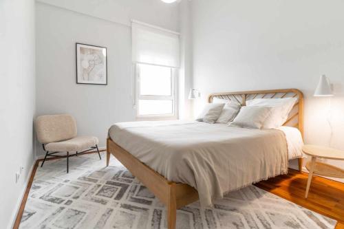 a white bedroom with a large bed and a chair at Apart T3 com piscina tenis ginasio e parq infant in Lisbon