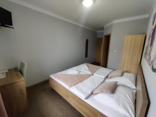 a bedroom with a bed with white sheets and pink pillows at Hotel Orlan in Bratislava