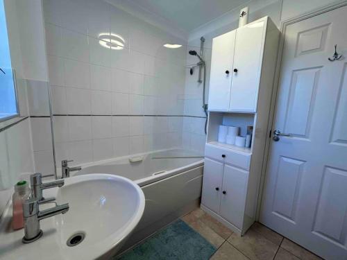 a bathroom with a sink and a tub and a white cabinet at Cozy Double Room with Parking and Full Kitchen in Southampton