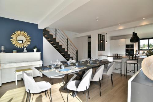 une salle à manger avec une grande table et des chaises blanches dans l'établissement L'escale de Rothéneuf - Jolie maison proche plage, à Saint-Malo