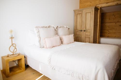 a bedroom with a white bed with pink pillows at Des sapins aux étoiles in Pierre-Percée