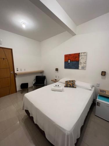 a bedroom with a large white bed and a desk at Pousada Escotilha in Arraial do Cabo