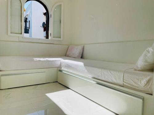 a white room with a bed and a mirror at Ksar Rimal par IMMO MARINA Vacances de Rêve J in Marina Smir