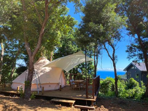 uma tenda com um deque de madeira com uma mesa e cadeiras em COUSCOUS Glamping Manazuru em Manazuru