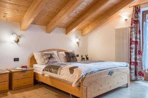 Schlafzimmer mit Holzbett und Holzdecken in der Unterkunft Casa Rossetti Big in Pozza di Fassa