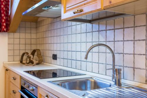 una cocina con fregadero de acero inoxidable y azulejos blancos en Casa Rossetti Big en Pozza di Fassa