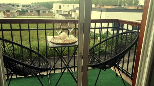 a balcony with two chairs and a table with wine glasses at Penzión Florens, Nesvady in Nesvady