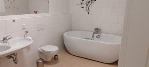 La salle de bains blanche est pourvue d'une baignoire, de toilettes et d'un lavabo. dans l'établissement Pentling Ferienwohnung, à Pentling