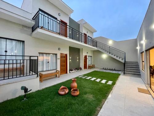 a house with a yard with vases on the grass at Pousada Saudadocê in São José da Barra